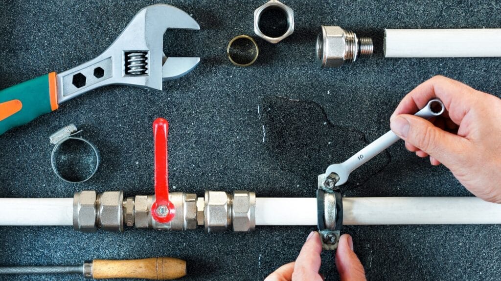 Plumber repairing a pipe valve with an adjustable wrench in Fort Lauderdale