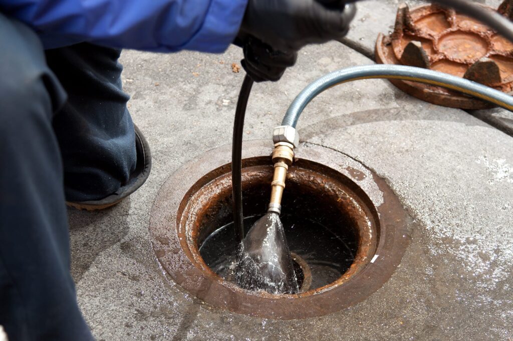 Plumber hydro jetting a sewer line through a manhole in Fort Lauderdale