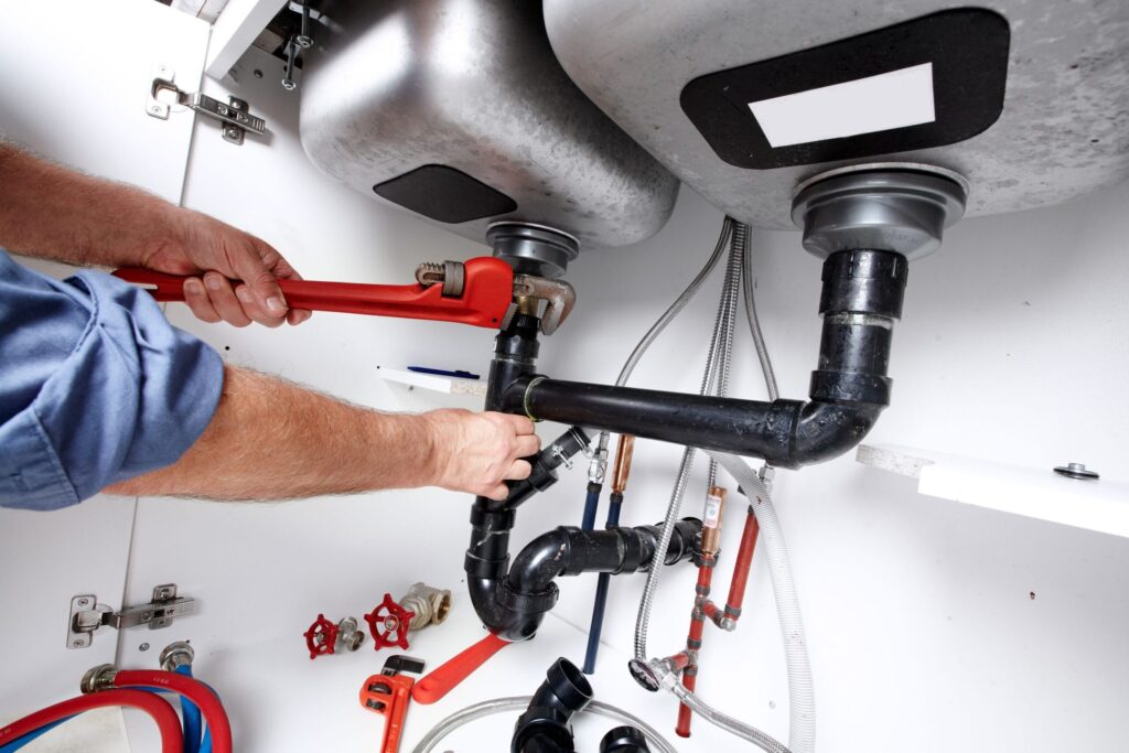 Plumber repairing drain pipes beneath a kitchen sink in Fort Lauderdale