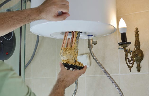 Technician removing mineral buildup from a water heater in Fort Lauderdale